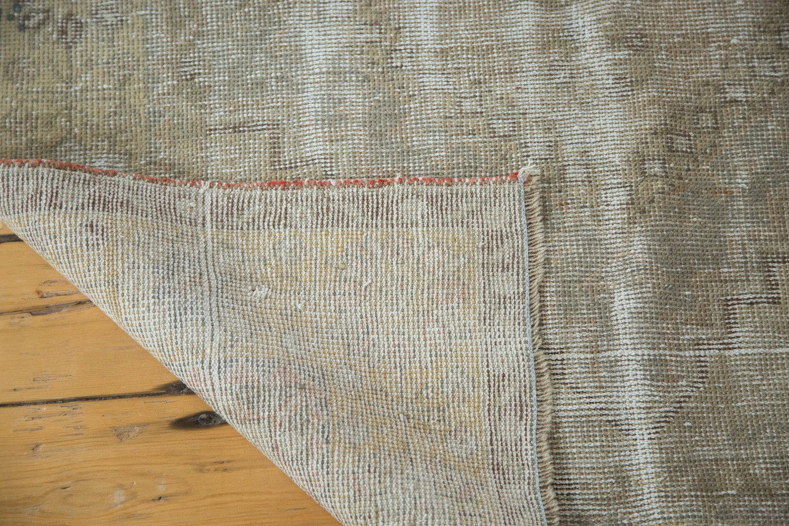Hand-knotted foundation, secured side, and distressed earth-tone pile of a Vintage Oushak rug.